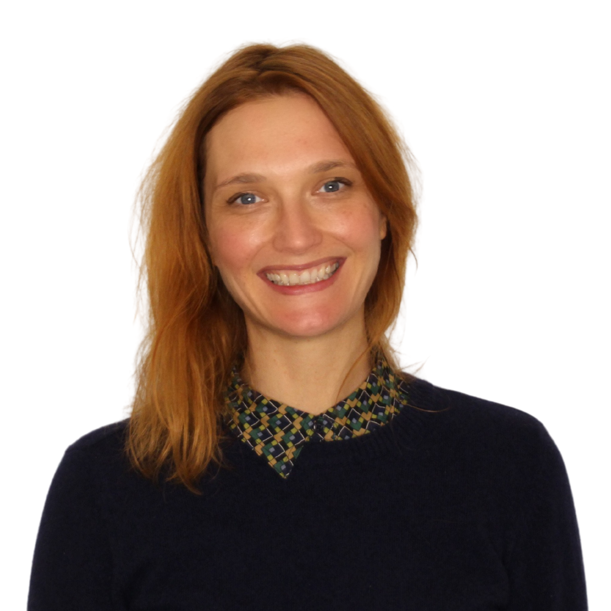 Amanda_Groschke Amanda Groschke trägt einen blauen Pullover und ein gemustertes Hemd darunter. Sie hat rotblonde schulterlange Haare und lacht in die Kamera.