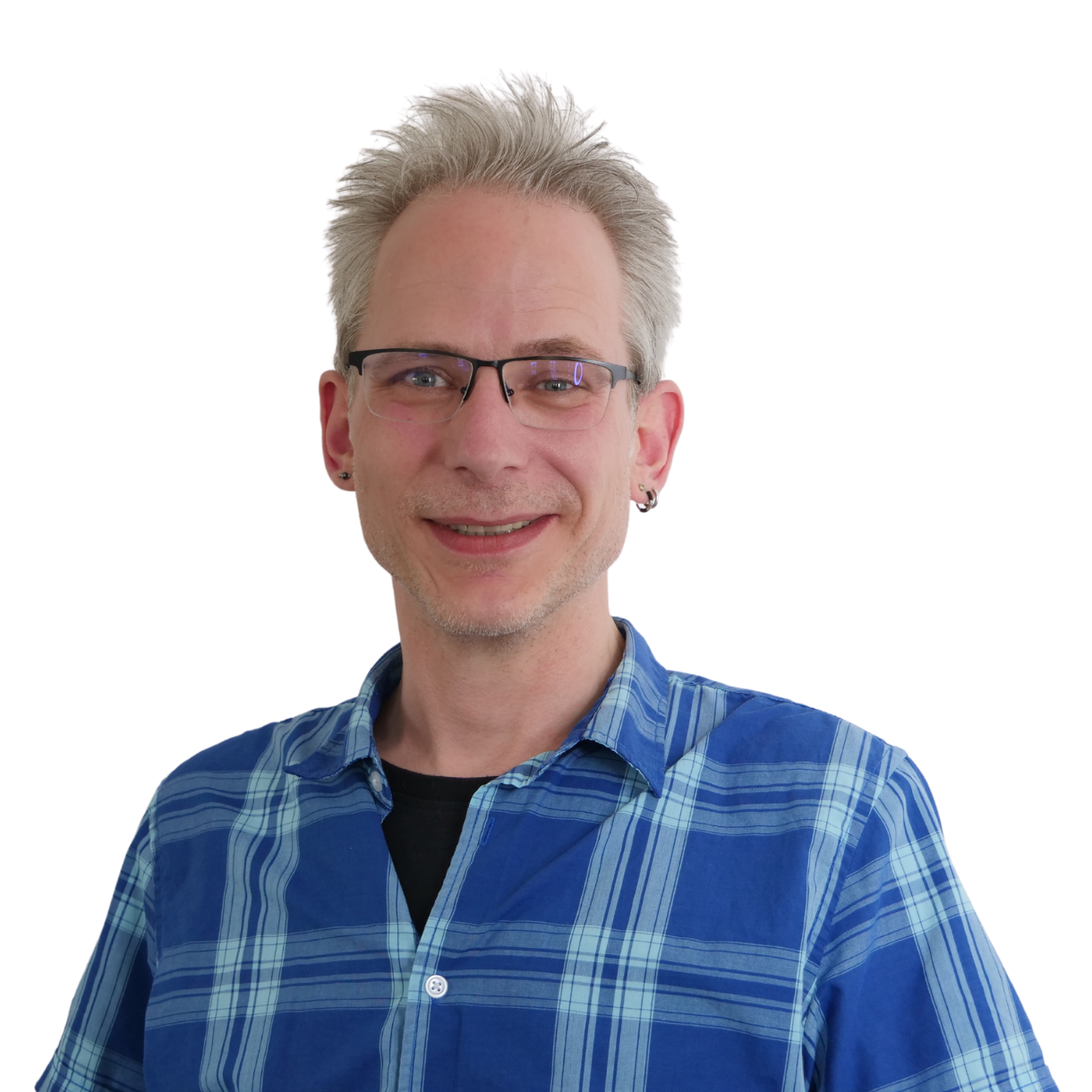 Martin_Petersen Porträt von Martin Petersen. Ein mittelalter Mann mit kurzen grauen Haaren lächelt in die Kamera. Er trägt eine Brille und ein blau-kariertes Hemd.