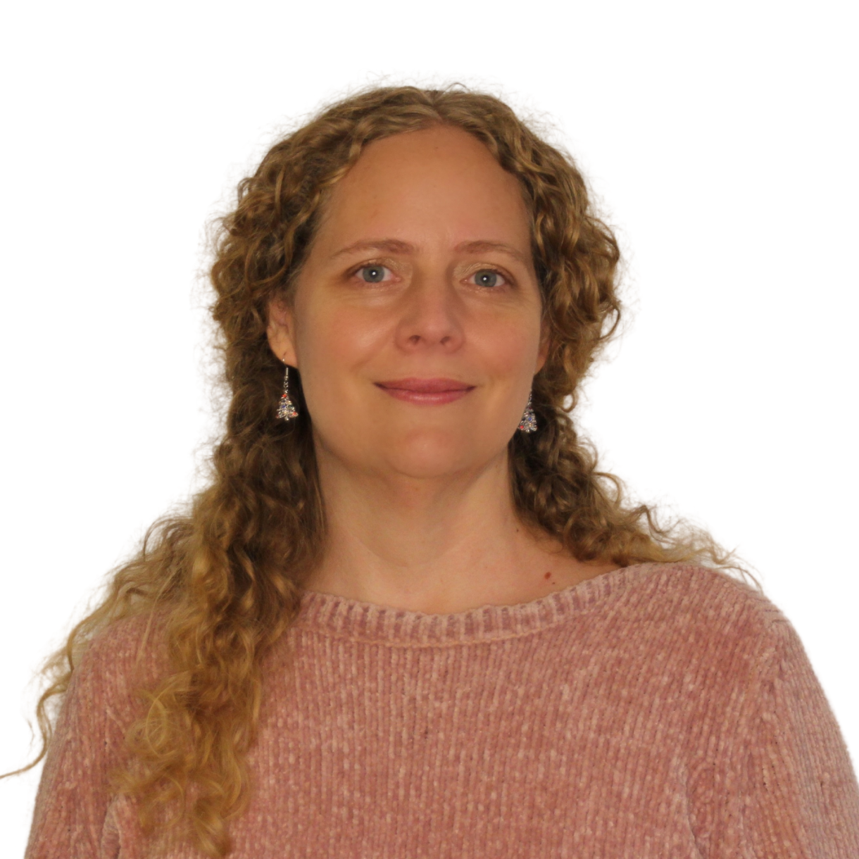Stefanie_Sudhaus Stefanie Sudhaus trägt einen rosa Pullover. Sie hat lange rotblond lockige Haare. Sie lächelt in die Kamera.