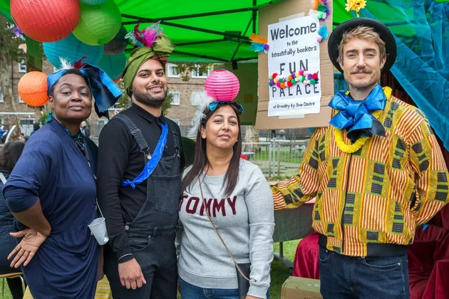 Vier Personen auf dem Fun Palaces Festival. Sie tragen bunte Accessoires wie Turbane oder eine Schleife um den Hals.