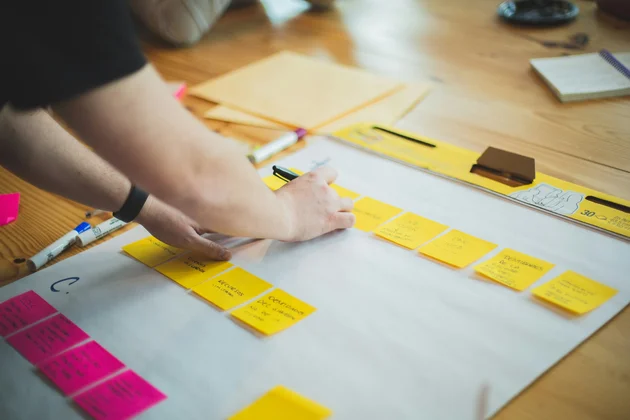 Auf einem Tisch werden bunte Post-its angeordnet.