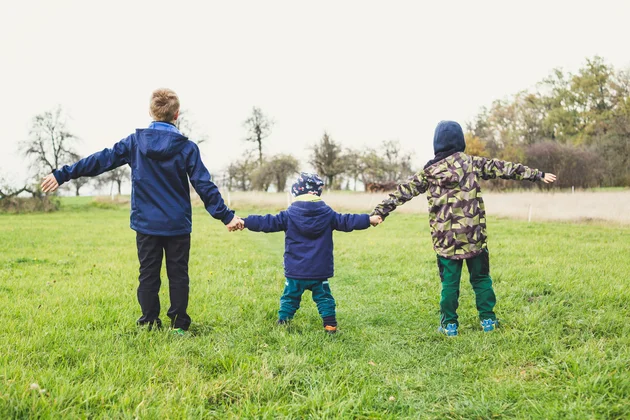 Drei Kinder halten sich an den Händen.