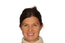 Porträt von Andrea Cederquist. Eine mittelalte Frau mit zurückgesteckten dunkelblonden Haaren lächelt in die Kamera. Sie trägt einen beigen Rollkragenpullover mit Norwegermuster. 