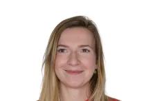 Porträt von Julia Krause. Eine junge Frau mit langen blonden Haaren lächelt in die Kamera. Sie trägt einen roten Pullover.