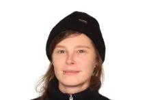 Helen Ruck trägt einen blauen Rollkragenpullover. Sie hat braune Haare, die zu einem Zopf geflochten sind. Sie trägt eine blaue Wollmütze und lächelt in die Kamera. An ihrer Unterlippe hat sie ein Piercing.