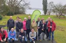 Gruppenfoto der Teilnehmenden des bewirk Netzwerktreffens. IM Hintergrund sind eine Wiese, Bäume und ein See.