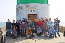 Das Team der Böll SH steht für ein Gruppenfoto vor dem grün weißen Leuchtturm auf Schleimünde.