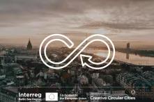 Im Hintergrund ist eine Stadt von oben in der Abenddämmerung zu sehen. Darüber ist ein Symbol gezeichnet, das Kreislauf symbolisiert. Unten sind die Logos von Interreg BSR, Creative Circular Cities und die EU-Flagge.