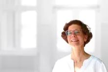 Portrait von Nicole Walter. Eine Frau mittleren Alters mit kurzen rotbraunen lacht in die Kamera. Sie trägt eine Brille und ein weißes Oberteil.