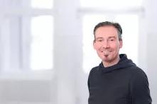 Portrait von Peter Wiebe. Ein mittelalter Mann mit kurzen grau-braunen Haaren. Er hat einen Dreitagebart und trägt einen schwarzen Hoodie.