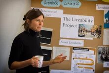 Andrea Cederquist, Mitarbeiterin des Projektes Liveability, steht vor einer vollgepinnten Wand und spricht.