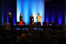 3 Vertreter*innen/Teilnehmer*innen des BSR Programms Cultural Pearls stehen gemeinsam auf einer Bühne. Diese ist Blau beleuchtet.