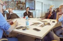 Eine Gruppe an Personen sitzt an einem Tisch. Sie scheinen sich zu unterhalten.