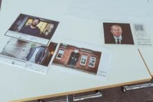 Vier Zettel mit verschiedenen Motiven liegend auf einem Tisch. 