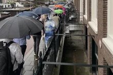 Teilnehmende einer Stadtfürhung in Groningen von hinten mit Regenschirmen über den Köpfen.
