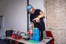 Ein Mann steht an einem DJ-Pult, das aus recycelten Materialien gebaut wurde.