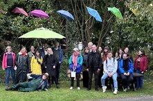 Das Böll-SH Team steht unter bunten Schirmen in einem Garten.