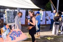 Menschen unterhalten und informieren sich an einem Festivalstand.