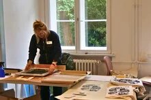 Berte Petersen steht an der Siebdruckstation und druckt.