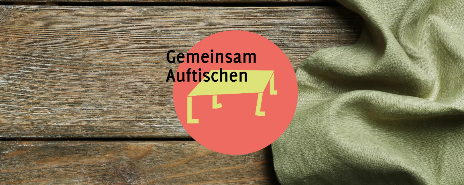 Logo Auftischen auf einem Hintergrund aus Holz. Im rechten Teil des Bildes ist grüner Stoff zu sehen.