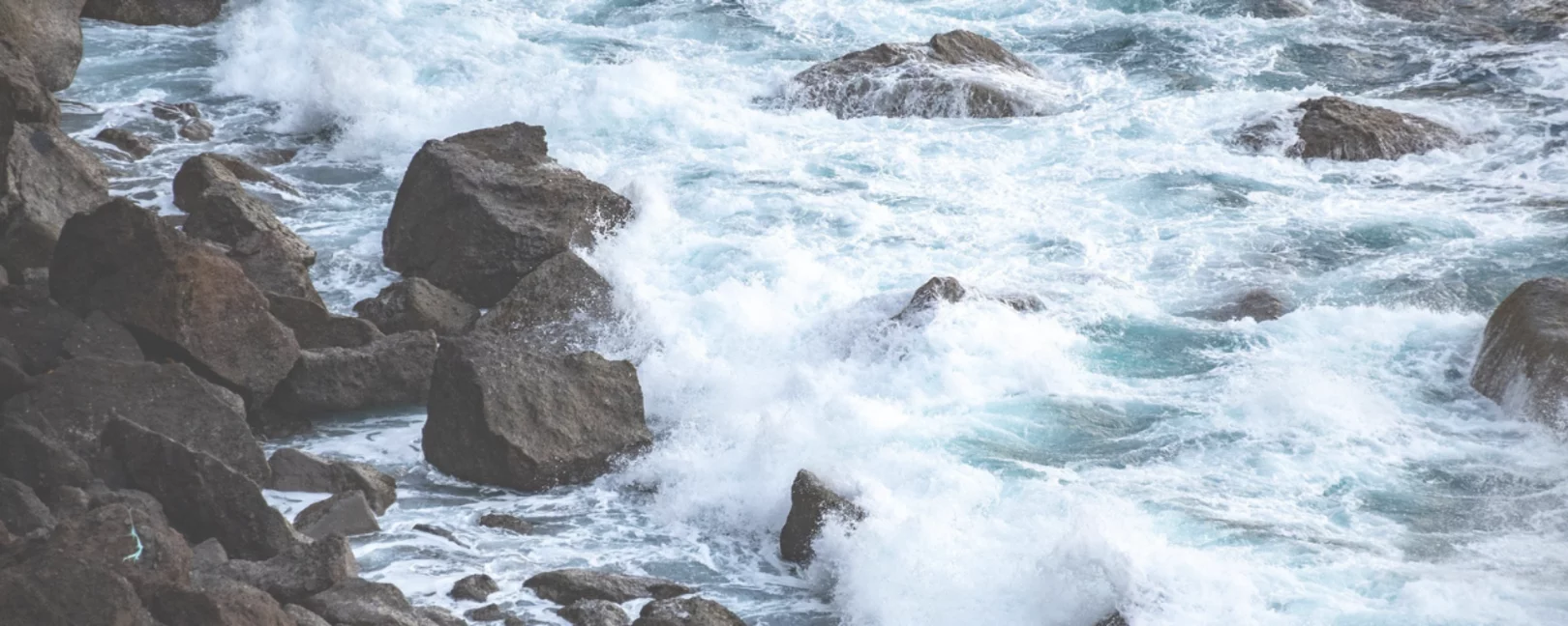 Große Felsen und Steine trotzen der tosenden Brandung. 