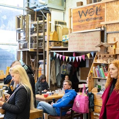 Eine Gruppe an Menschen steht in einer Holz-Werkstatt.