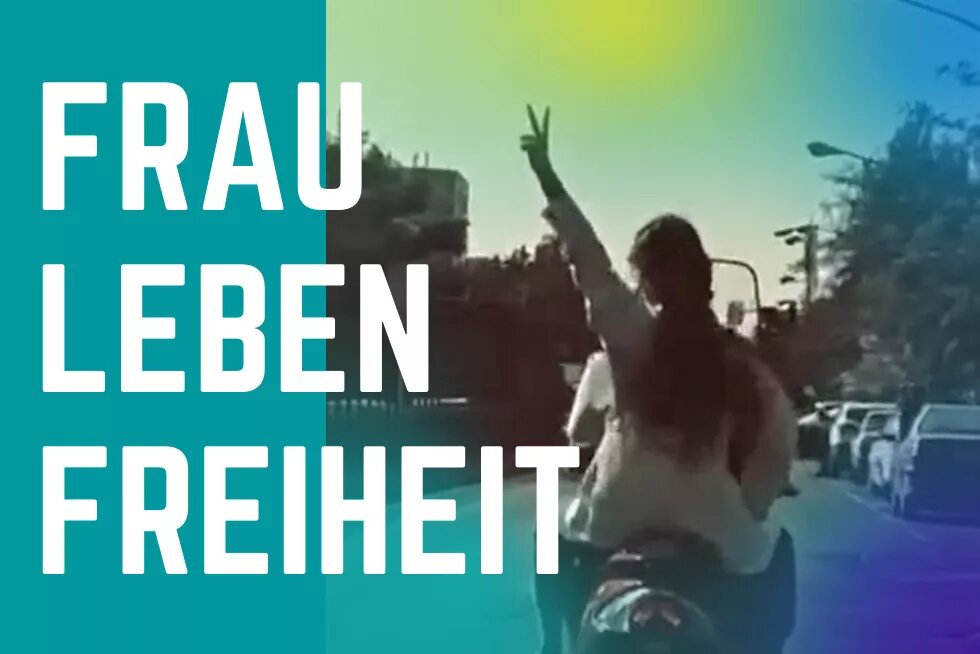 Frau, Leben, Freiheit Eine junge Iranerin fährt ohne Hijab Motorroller und reckt ihre linke Hand zum Peace-Zeichen in die Luft. Links daneben steht groß: "Frau, Leben, Freiheit".