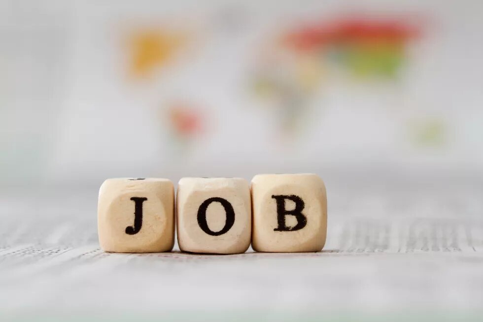 Holzwürfel mit schwarzen Buchstaben auf einem Tisch, die das Wort "Job" bilden.