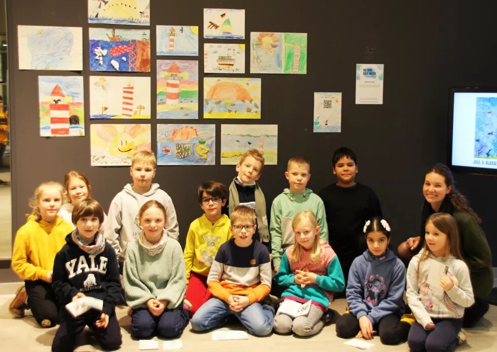 Die 2c der Grundschule Russee sitzt vor ihren gemalten Bildern für den Kunstwettbewerb "DU UND DAS MEER".
