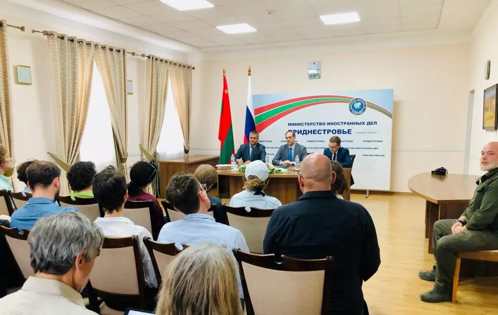 Besuch in Tiraspol mit Vertreter*innen der Politik. Vorne sitzen Leute am Podium, neben ihnen sind die russische und moldauische Fahne.