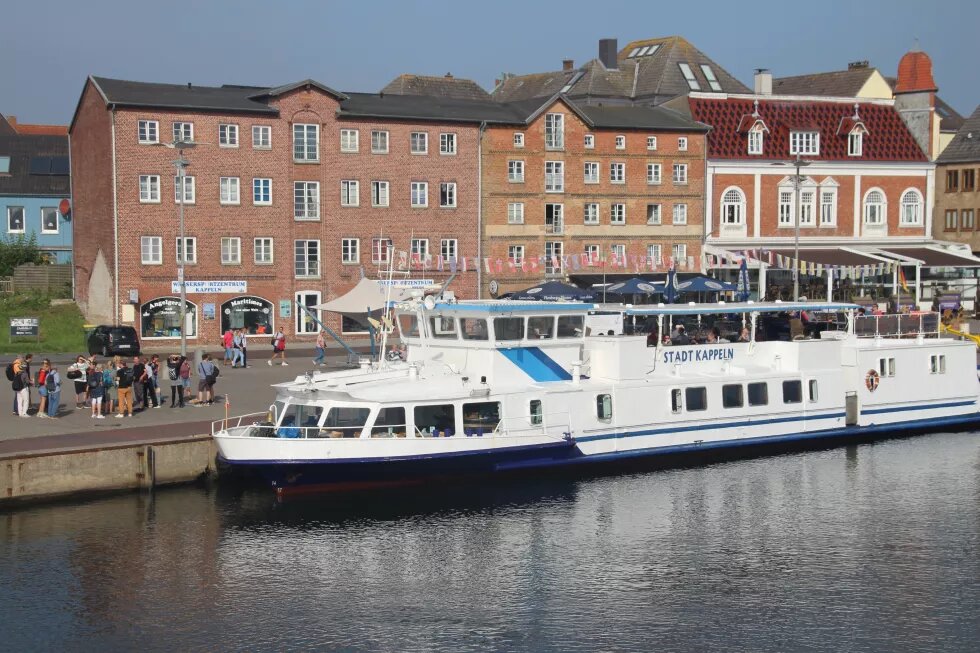 Am Kappelner Hafen liegt das Ausflugsschiff MS Stadt Kappeln. Dahinter sind rote Speicherhäuser.