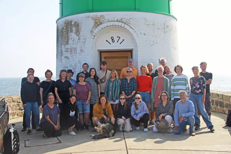 Das Team der Böll SH steht für ein Gruppenfoto vor dem grün weißen Leuchtturm auf Schleimünde.