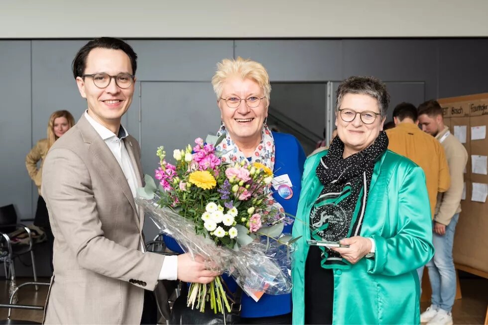 Awardübergabe Felix Schartner Giertta (CBSS, Cultural Pearls) übergibt einen Blumenstrauß an Annette Wiese-Krukowska (Referat Kreative Stadt Kiel) und Bürgermeisterin Renate Treutel, die den gläsernen Award in den Händen hält.