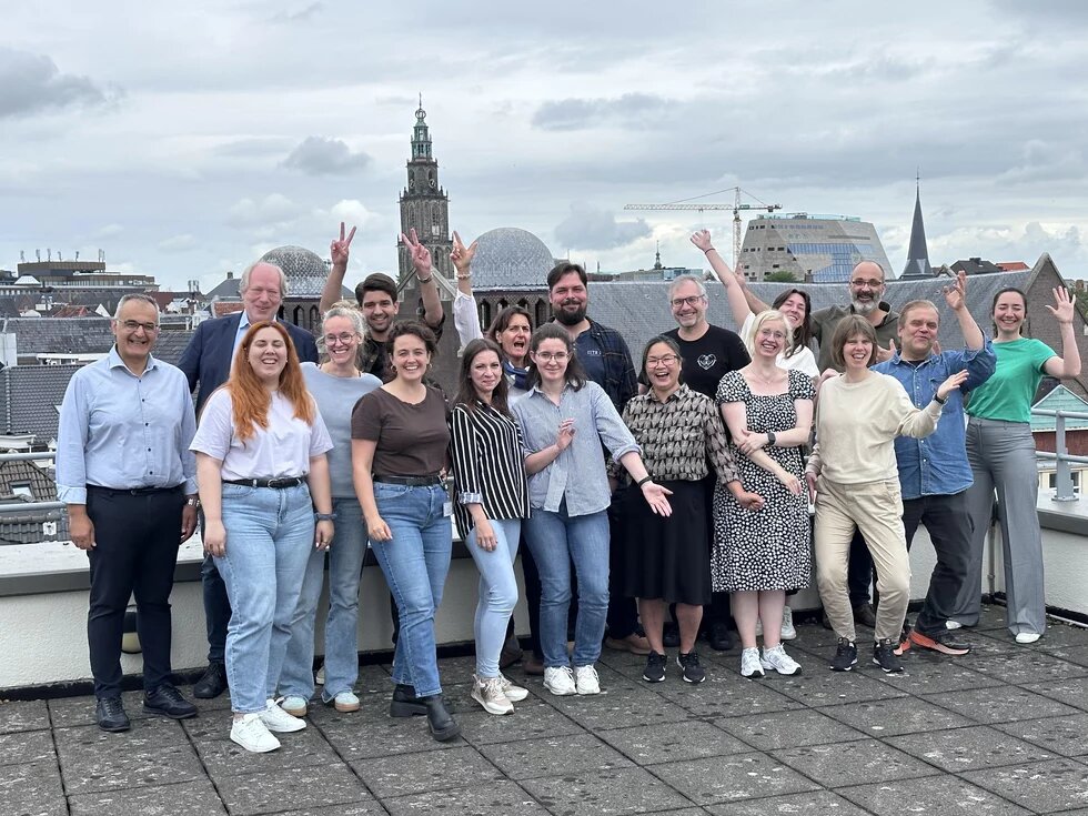 Teilnehmende des Projekts UrbCitizenPower stehen auf einer Dachterasse in Groningen. Hinter ihnen ist ein Kirchturm und das Stadtpanorama zu sehen. 
