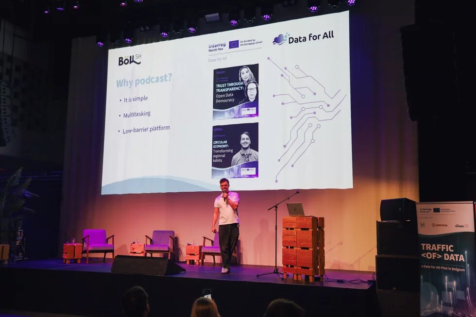 Max Nettlau steht auf einem Podium und hält einen Vortrag bei der Abschlusskonferenz von Data for All zum Thema Podcasts..