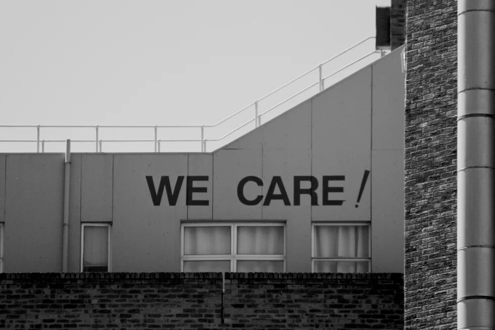 Auf einer Hausfassade steht "We care!"