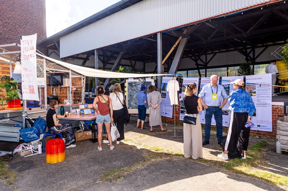 Waterkant Festival: Leute stehen an einer Outdoor-Ausstellung. Einige unterhalten sich, andere lesen informative Banner.