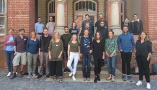 Ocean Summit Hackathon Eine Gruppe vieler Menschen steht vor einem historischen Backsteingebäude. Alle schauen in die Kamera.