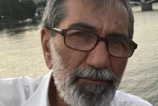 Nami Tabari Nami schaut ernst in die Kamera. Er hat grau-melierte Haare und einen Bart, er trägt eine Brille und ein weißes Hemd.